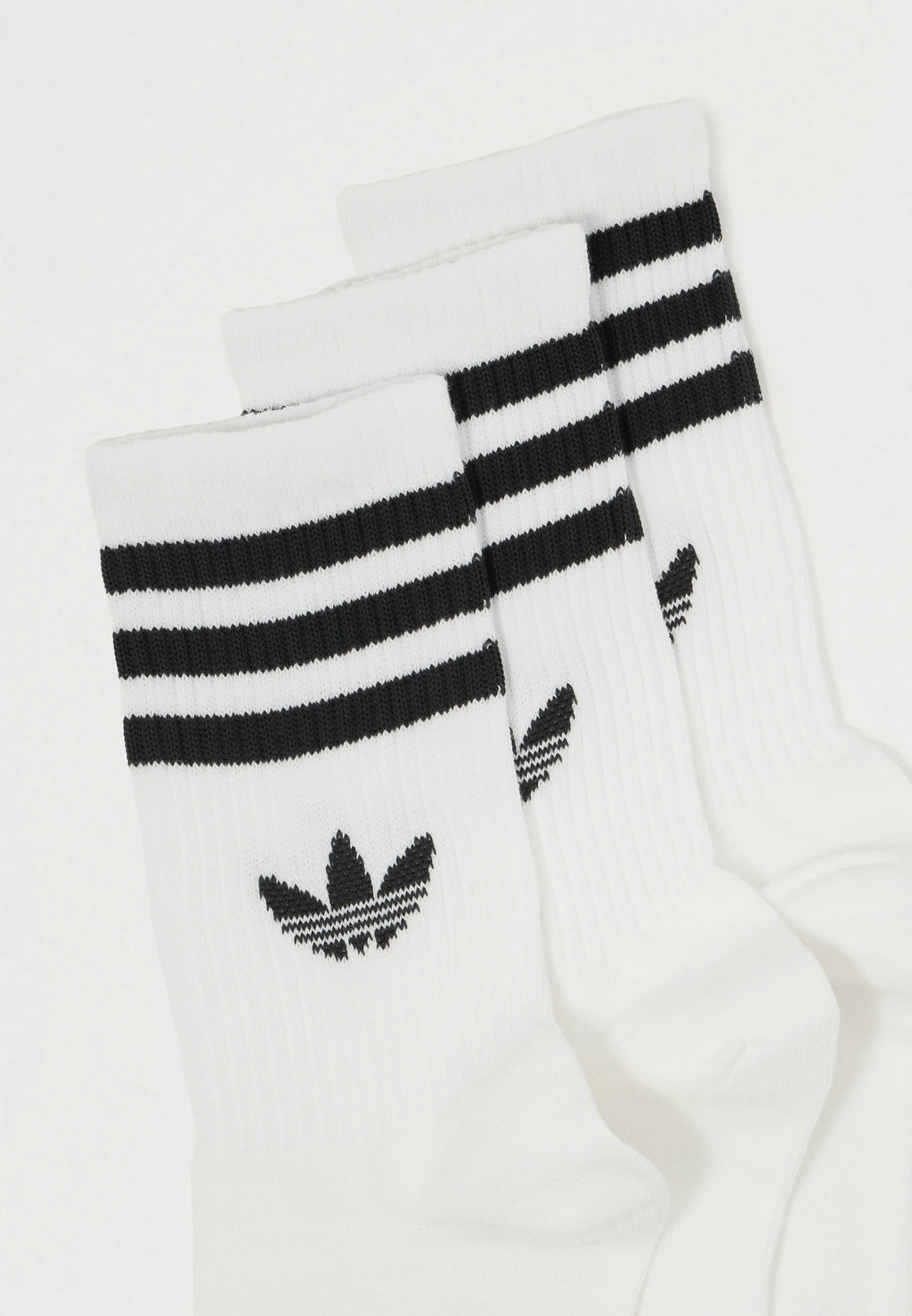 Three pairs of white socks featuring black horizontal stripes at the top and a black logo with three leaves, ribbed texture throughout.