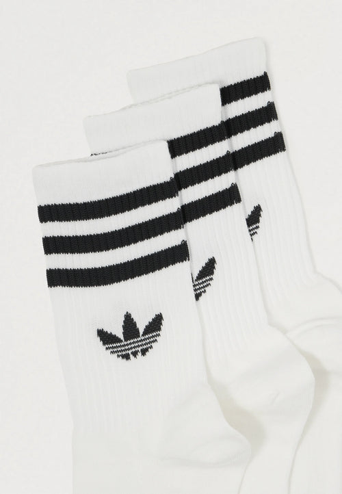 Three pairs of white socks featuring black horizontal stripes at the top and a black logo with three leaves, ribbed texture throughout.