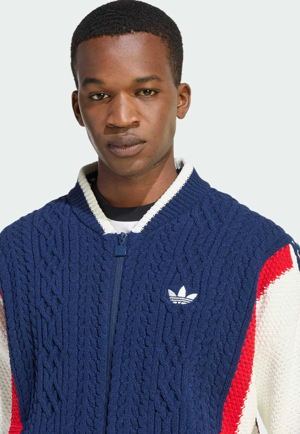 Maglione navy a treccia con zip bianca, con accenti a pannello rossi e bianchi e un piccolo logo bianco sul lato sinistro del petto.